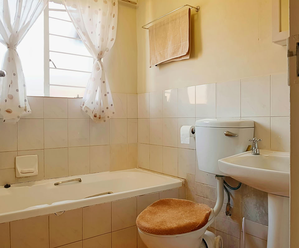 Bright and tidy bathroom featuring a bathtub, toilet, and washbasin with natural light.
