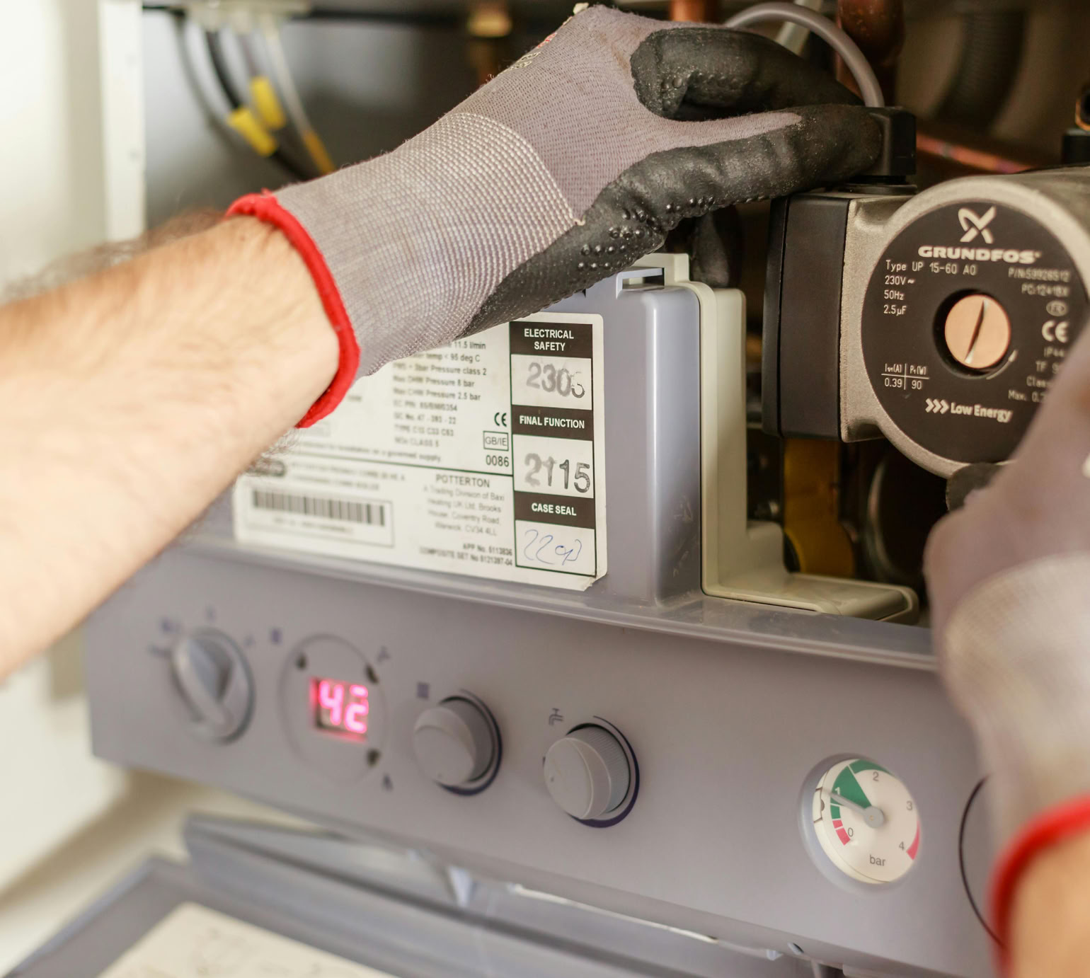 Close-up of hands adjusting a boiler system with precise instrumentation, showing maintenance work.