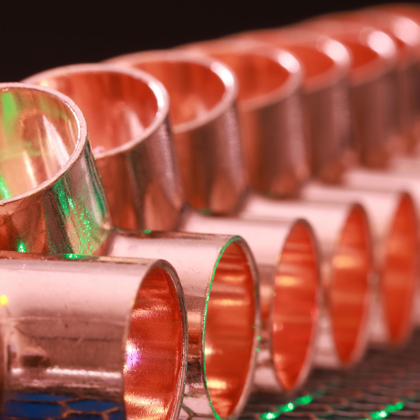 Copper plumbing fittings arranged in a row, showcasing metallic texture and industrial detail.